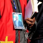 1 Papa Luyada holding Bible wearing toge and memorial photo
