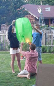 Allysa and Austin assist Allen in lighting a floating lantern.