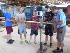 Bobby, Ben and Timothy hold the pipe while Nate drills with supervision from Ron